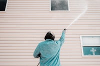 a man spraying a house with a pressure washer