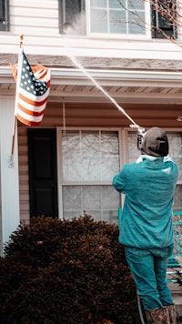 a man spraying a house with an american flag