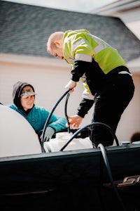 a man in a yellow jacket is putting a hose on a boat